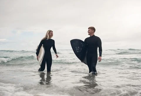 We surf because its fun. a young couple out at the beach with their surfboards. Photos
