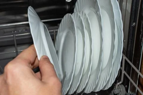 We take out already clean white plates from the dishwasher Stock Photos