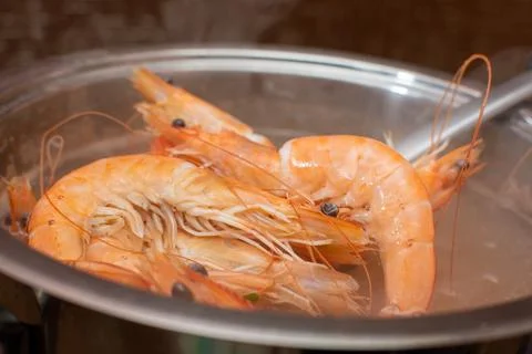 We take out the cooked boiled shrimp from the pan Stock Photos