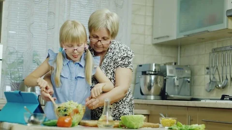 We work together. The girl of 6 years together with the grandmother do a salad Stock Footage 74913397