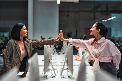 We work together as a team. Two beautiful business women give each other five Stock Photos