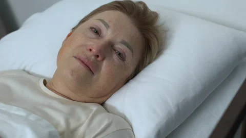 Weak crying lady lying in bed and looking at camera, hospice center, despair Stock Footage 105879678