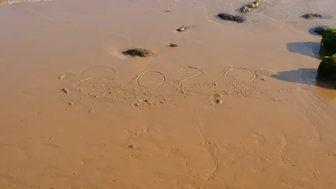 Weak twenty twenty written on wet sand, sea water wash away Stock Footage 128663896