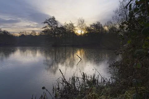 Weak winter sun rises over Mill Lakes on a December morning. Foto stock