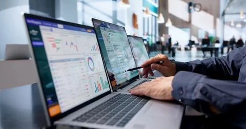 Wealth Advisor Studies Client Portfolio Data Closely On Laptop At Office. Stock Photos