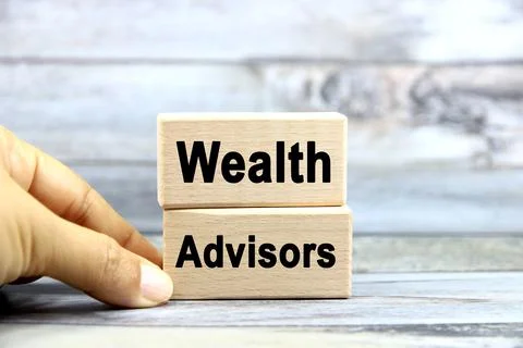 Wealth Advisors wording or text on wood block with hand on grey background... Stock Photos