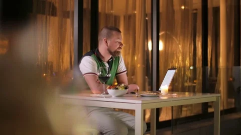 A wealthy freelancer man works at a computer on the terrace of his villa, at Stock Footage 77751107
