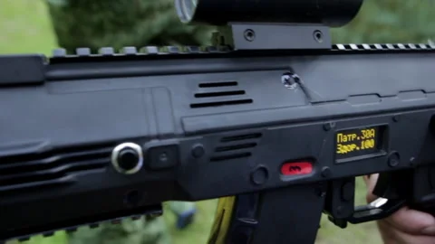 A weapon with a digital display in the hands of a military man with a forest Stock-Footage 219610306