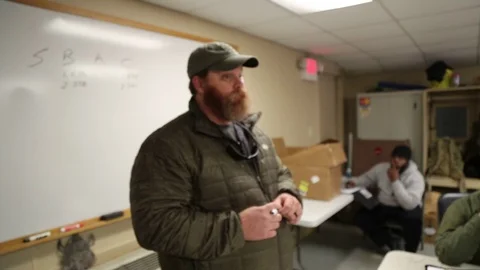 Weapons Instructor Answers Trainee in Classroom Stock Footage 70561848