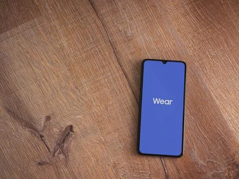 Wear - Galaxy Wearable app launch screen on smartphone on wooden background Stock Photos