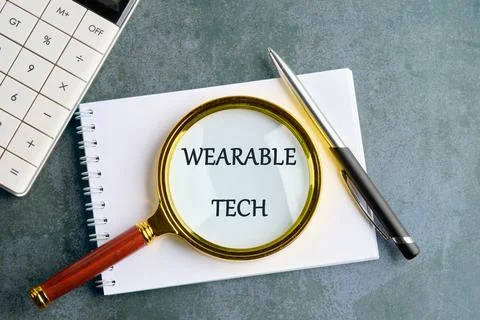 WEARABLE TECH concept word in a clean notebook on a gray background, top view Stock Photos