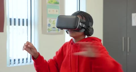 Wearing VR headset, red hoodie, African American teen gesturing and manipulating Stock Footage 340656355