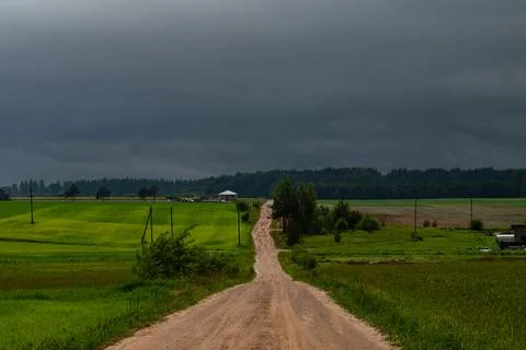 WEATHER - Dramatic black rain clouds over fields and country road. Stock Photos