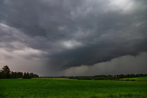 WEATHER - Dramatic black rain clouds over fields and country road. Stock Photos