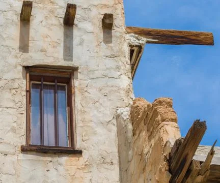 Weathered adobe pueblo with window covered by curtain Stock Photos