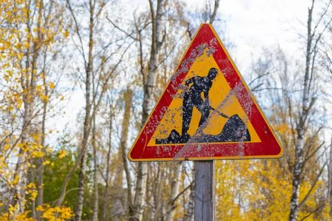A weathered and dirty triangular road works sign stands along a road in Espoo Stock Photos