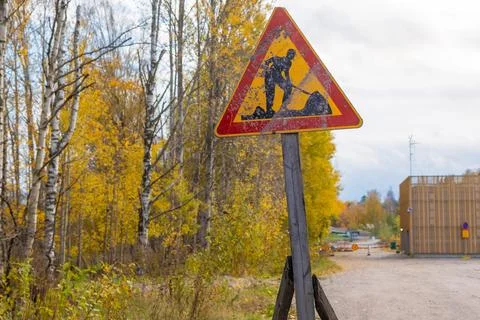 A weathered and dirty triangular road works sign stands along a road in Espoo Stock Photos
