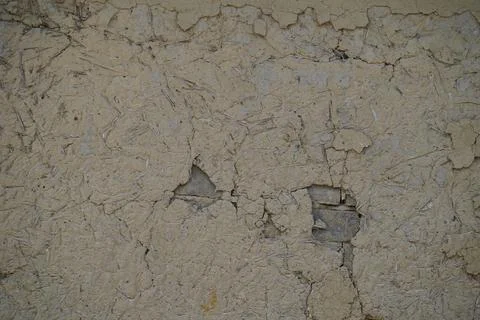 Weathered beige mud wall texture with cracks and peeling plaster surface backgro Stock Photos