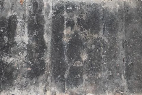 A weathered black cement surface with visible marks and stains. Stock Photos
