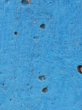 Weathered blue painted surface with deep holes texture background Stock Photos