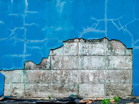 Weathered Blue Painted Wall with Exposed Concrete Tiles and Peeling Paint Foto stock