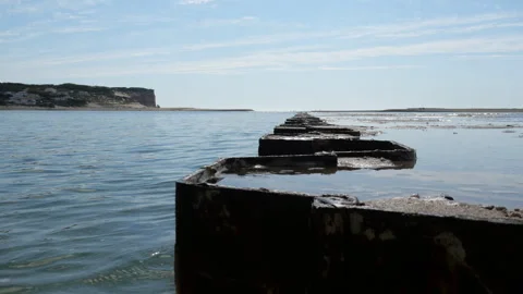 Weathered Breakwater Toward Dramatic Cliffs at Foz do Arelho, Low Angle Shot Stock Footage 340558796