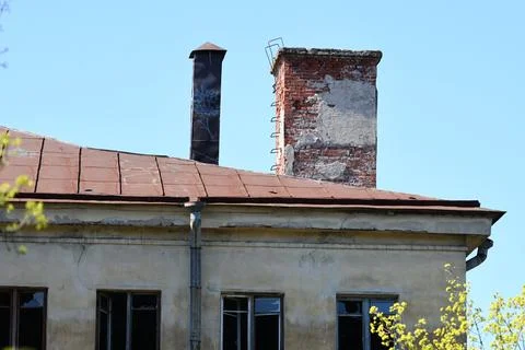A weathered brick building with a functional chimney and rusted roof, great for Foto stock