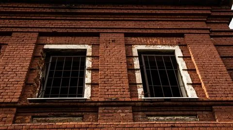 A Weathered Brick Building Notable for Its Gated Windows and Unique Stock Photos