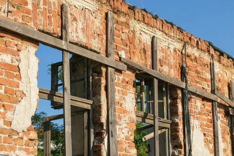 Weathered brick facade of abandoned building with wooden window frames and .. Stock Photos