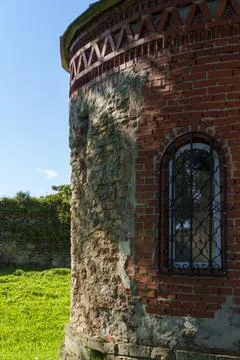 Weathered brick tower with arched window and iron bars Foto stock