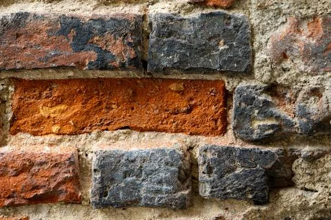 Weathered brick wall with irregular masonry shows rough textured surfaces. 스톡 사진