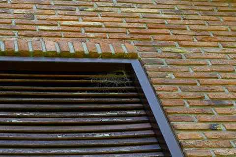 Weathered brick wall meets dark metal grille Stock Photos