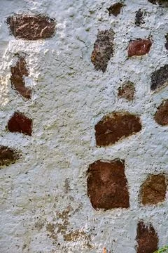 Weathered brick wall showing rough white plaster and earthy texture Stock Photos