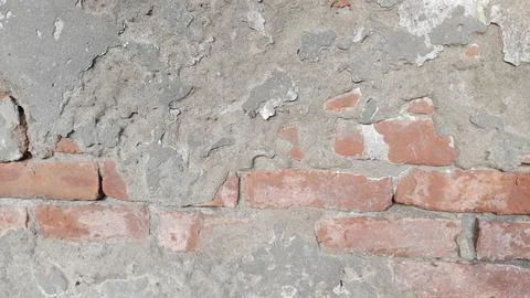 Weathered brick wall texture with cracked plaster and exposed red masonry Stock Photos