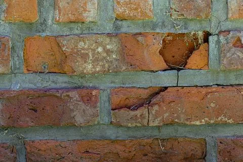 Weathered brick wall with visible cracks and moss Stock Photos