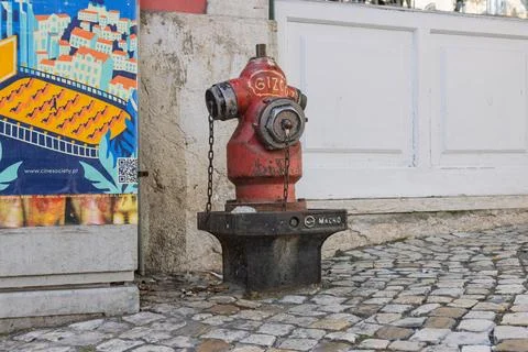 A weathered, bright red fire hydrant sits on a traditional cobblestone street Stock Photos