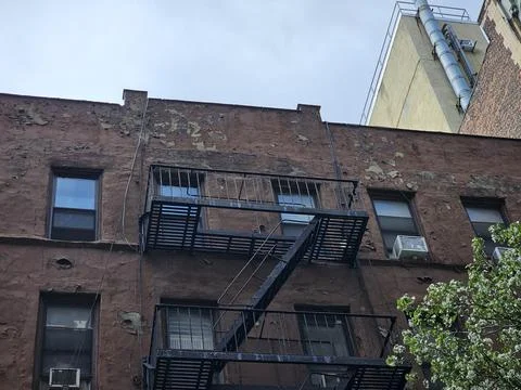 Weathered brownstone facade with fire-escape landings Stock Photos