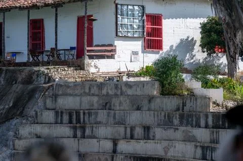 A weathered building with red accents sits overlooking a tiered stone struc.. Foto stock