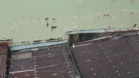 Weathered Building Wall with Rusty Metal Roof During Rainfall Stock Footage 291701960