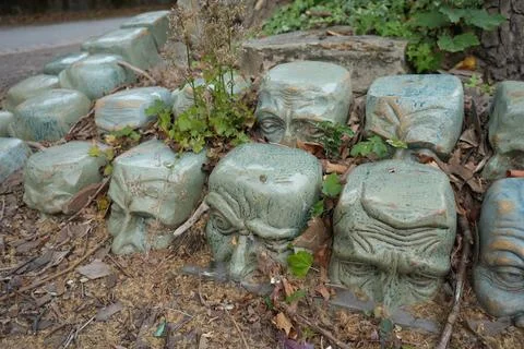 Weathered Ceramic Faces Among Leaves In A Garden, Derby, England Stock Photos