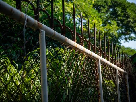 Weathered Chain Link Fence with Rusty Metal Security Spikes on Top Stock Photos