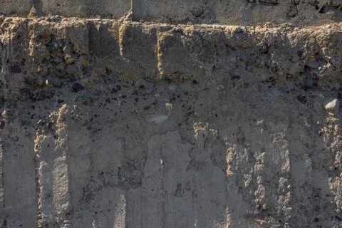 Weathered Cheap Uneven Concrete Surface with Pebbles under tangential harsh 库存照片