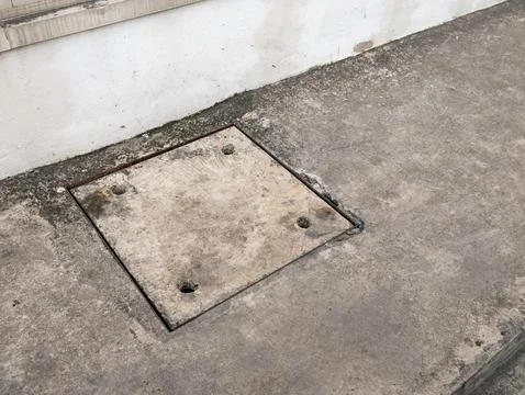 Weathered Concrete Access Panel on Ground with Stains and Aging Foto stock