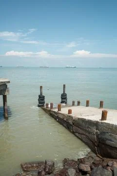 Weathered dock extends into calm, greenish sea Stock Photos