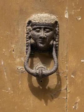 Weathered Door Knocker, a human face and headdress in classical style on a .. Stock Photos