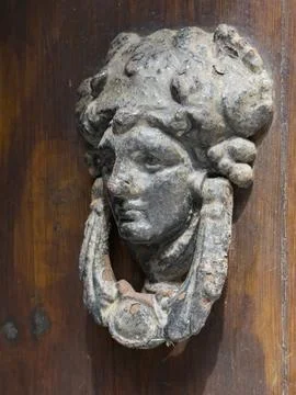 Weathered Door Knocker, a relief shape of a woman's head, classical style. Stock Photos