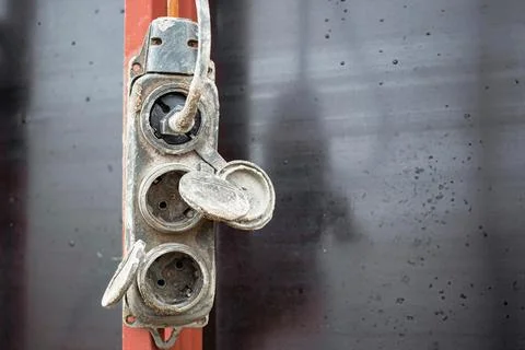 A weathered electrical outlet hangs on a wall, showing dirt and age. It featu Photos