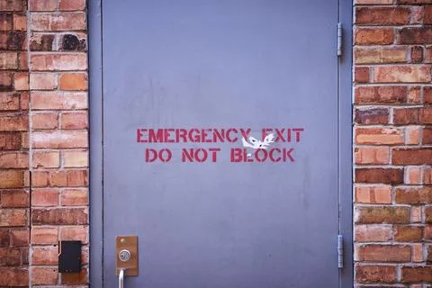 Weathered Emergency Exit on Brick Wall, Eye-Level View 스톡 사진
