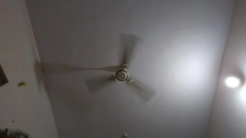 A weathered fan rotates slowly over a desk in a public facility, highlighting th 스톡 동영상 343784306
