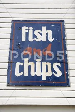 Weathered fish and chips sign at seaside Stock Photos